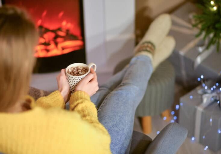 Beautiful young woman drinking hot chocolate at home on Christmas eve